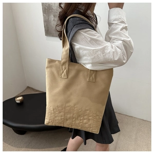 Détail d'un grand sac cabas en toile kaki avec broderie blanche et larges bandoulières