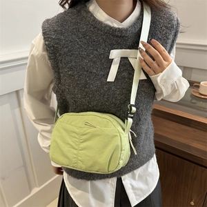 Light green nylon crossbody bag with pleated texture and adjustable strap on a model