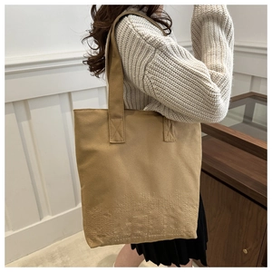 Detail of embroidered IKTMU logo on a khaki canvas tote bag with textured fabric