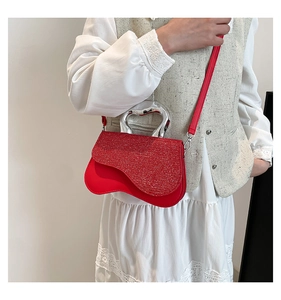Detail of red crossbody bag with sequined flap and heart-shaped silver metal handle