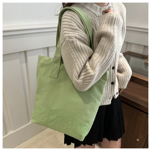 Detail of light green canvas tote bag featuring subtle dotted embroidery on the bottom