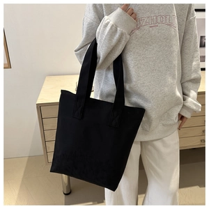 Close-up of durable black canvas tote bag showing the texture and minimalist shoulder strap