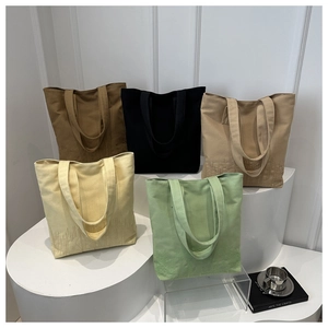 Five colored canvas tote bags with pixelated textures and minimalist design in studio