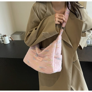 Detail of pink canvas crossbody bag featuring colorful embroidery and logo patch