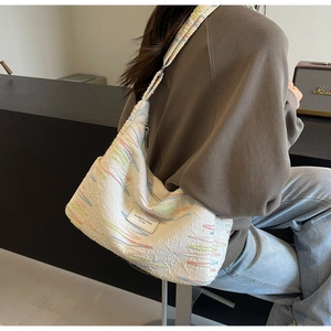 Close-up of beige canvas tote bag featuring colorful embroidery and logo patch detail