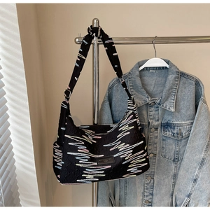 Detail of black canvas bag with colorful wavy embroidery and metal buckle on strap