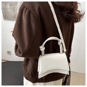 Detail of white hourglass handbag with knotted handle and adjustable leather strap