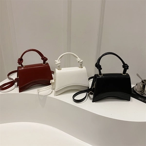 Three elegant leather mini handbags in red, white, and black with unique curved base
