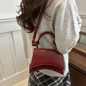 Glossy burgundy patent leather hourglass shoulder bag with adjustable strap and top handle