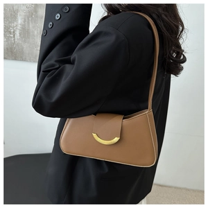 Brown shoulder bag with a gold buckle shown from the side on a model in a black blazer