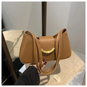 Detail of caramel brown leather shoulder bag featuring a polished gold semicircular buckle
