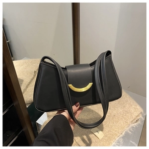 Close-up of black matte leather shoulder bag with a curved gold metal buckle detail