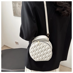Detail of white quilted round shoulder bag with faux leather texture and top handle