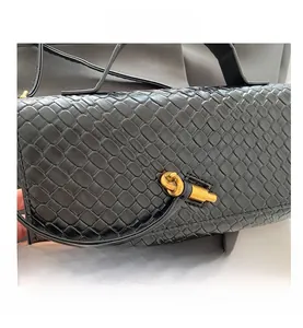 Macro shot of black woven texture with gold twist lock on women's baguette bag