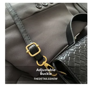 Macro shot of gold adjustable buckle and lobster clasp on black woven leather bag