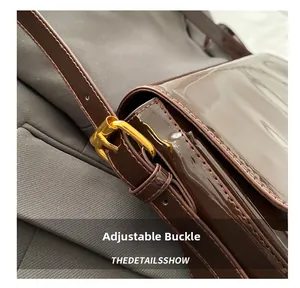 Detail of adjustable golden buckle and brown patent leather strap on shoulder bag