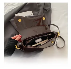 Detail view of coffee patent leather shoulder bag interior with spacious compartments