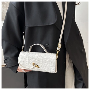 Detail of white woven texture handbag featuring a gold twist lock and a short top handle
