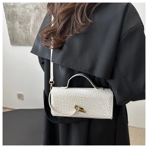 White woven crossbody bag with gold buckle shown on model wearing a black coat