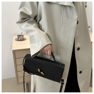 Close-up of black woven texture shoulder bag with gold twist lock on a beige trench coat