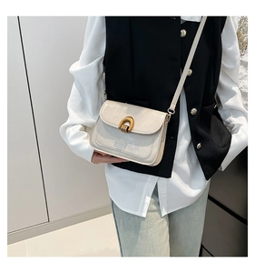 Model wearing a retro beige leather crossbody bag with vintage gold U-shaped buckle