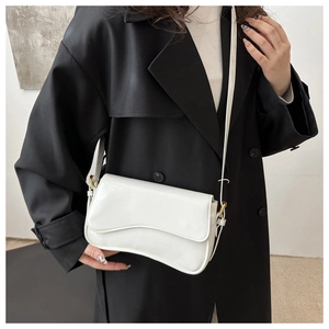 Close-up of white glossy patent leather bag with wavy flap and gold hardware detail