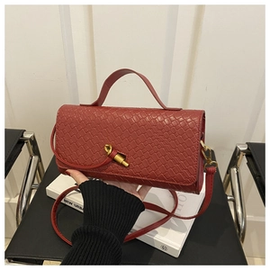 Detail of deep red woven texture bag featuring a unique gold-tone metal twist lock clasp