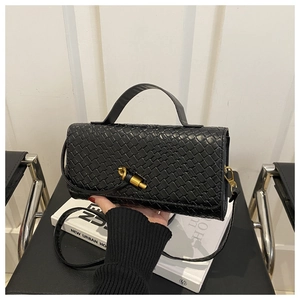 Close-up of black woven texture handbag with a unique golden twist lock detail