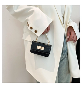Détail du sac en cuir gaufré crocodile avec anse en perles porté par un mannequin en blazer