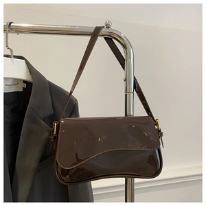 Détail du sac en cuir verni marron foncé avec rabat ondulé et boucles dorées