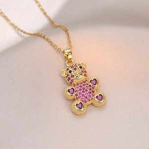 Collier doré avec pendentif ours en zircon rose sur fond de soie champagne