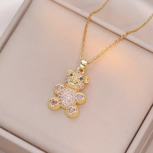 Collier ours en peluche doré avec zircons cœurs roses sur une boîte à bijoux beige