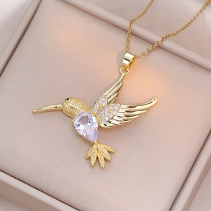 Golden hummingbird necklace with purple pear-shaped zircon on a pink jewelry gift box