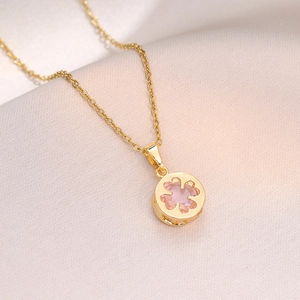 Golden titanium steel necklace with pink clover zircon pendant on soft silk background