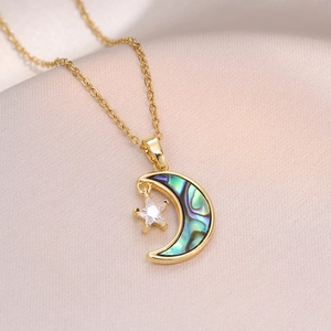 Élégant collier doré avec lune et étoile en nacre sur fond de tissu satiné rose doux