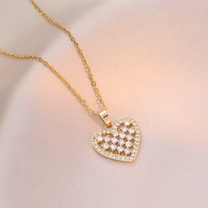 Collier pendentif cœur doré serti de zircons brillants sur fond de soie champagne