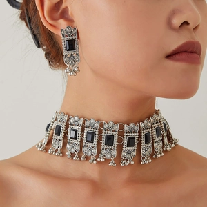 Detail of vintage geometric jewelry set with black gemstones and metallic tassels