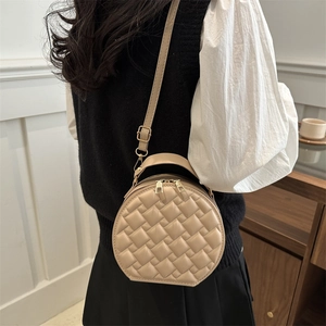 Beige round quilted crossbody bag with adjustable strap and golden dual zippers