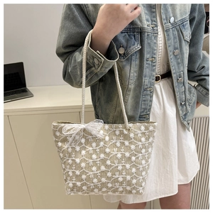 Détail du sac cabas en paille avec broderies florales 3D blanches et nœud en dentelle
