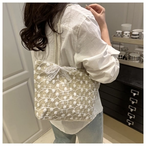 Sac cabas en paille avec broderie florale porté à l'épaule pour un look d'été chic