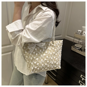 Détail de la broderie de fleurs en dentelle et de l'anse en corde du sac en paille