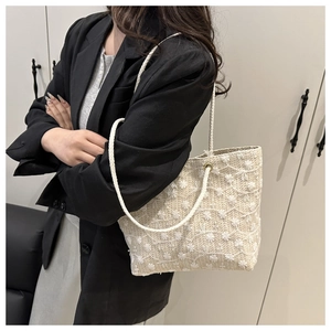 Vue détaillée du sac cabas beige tissé avec broderies florales 3D blanches et anses en corde