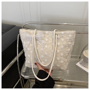 Détail du sac cabas tissé avec broderie de marguerites et un nœud en dentelle blanche