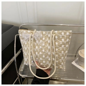 Détail d'un sac cabas tissé avec broderie florale blanche et nœud en dentelle décoratif