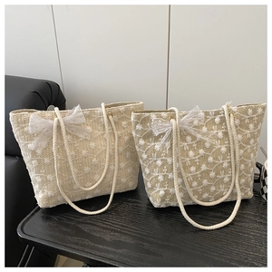 Détail de sacs fourre-tout en paille avec broderie florale et nœuds en dentelle