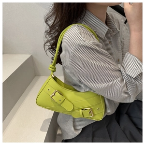 Close-up of bright green leather underarm bag with large silver buckles and knot detail