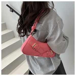 Detail of a bright pink crescent shoulder bag with polished gold buckles and Y2K aesthetic