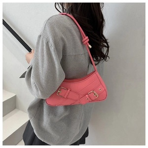 Detail of pink faux leather underarm bag with double strap buckles on a striped shirt