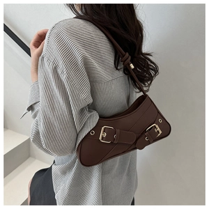 Model wearing a retro dark brown saddle shoulder bag with decorative metal buckles