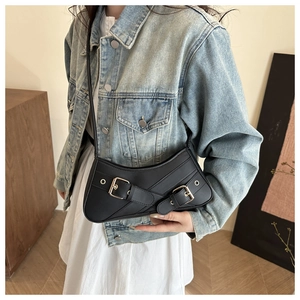 Sac sous le bras rétro en cuir noir avec boucles dorées porté sur veste en jean et robe